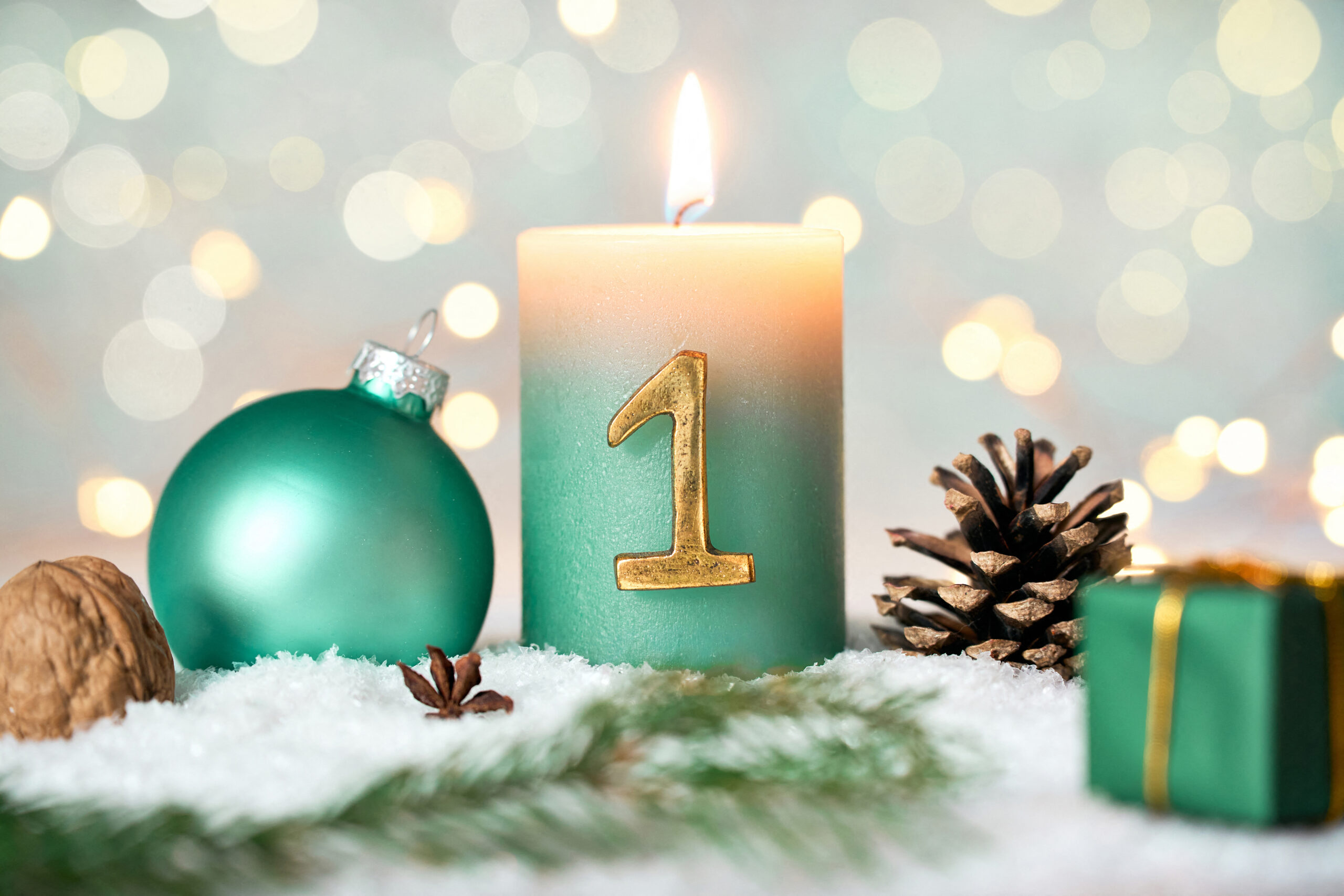erster advent mit grüner adventskerze im schnee, dekoriert mit kugel, tannenzweig und geschenk – schönes adventsbild zum 1. advent