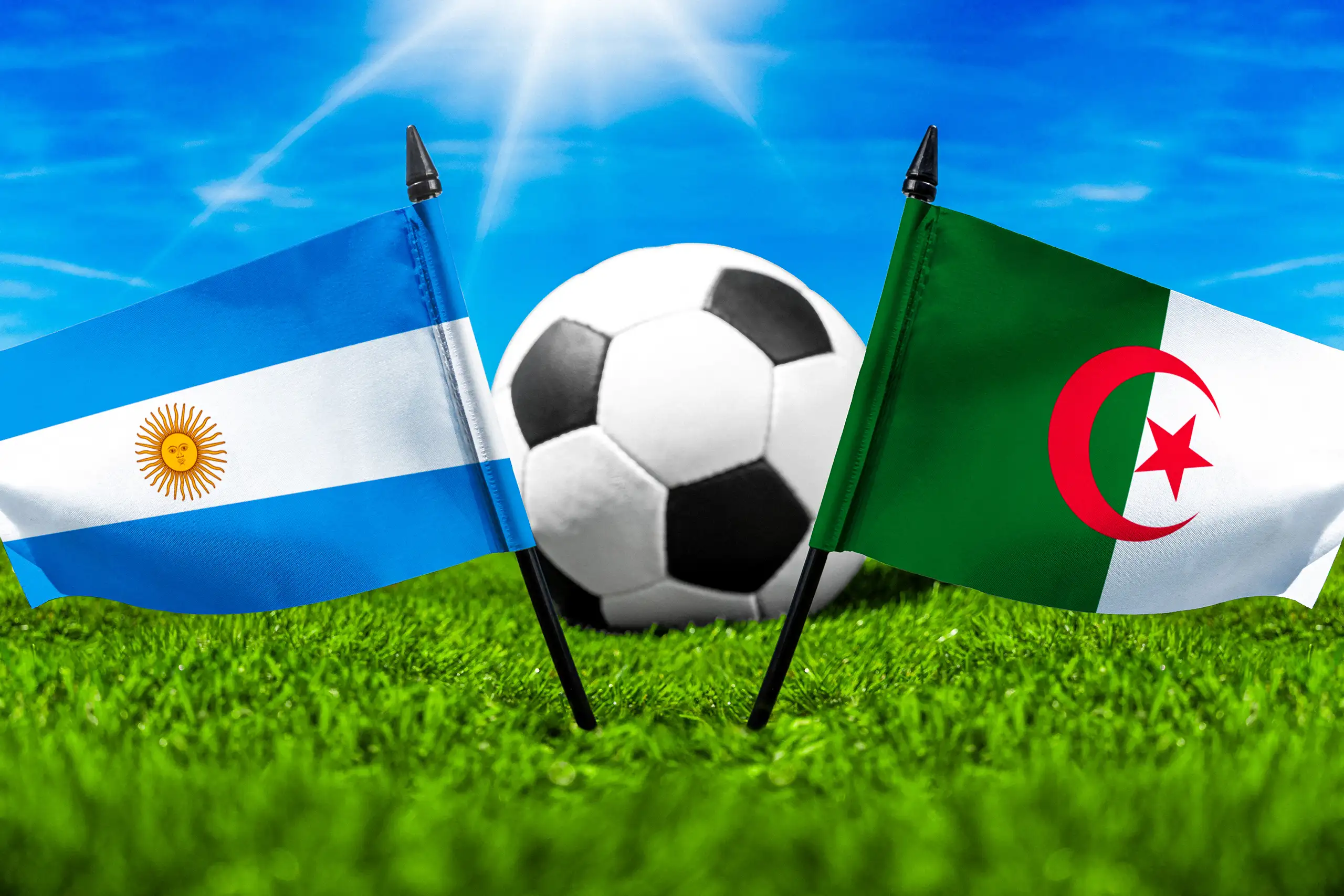 argentinische und algerische flagge mit fußball auf grünem rasen unter blauem himmel.
