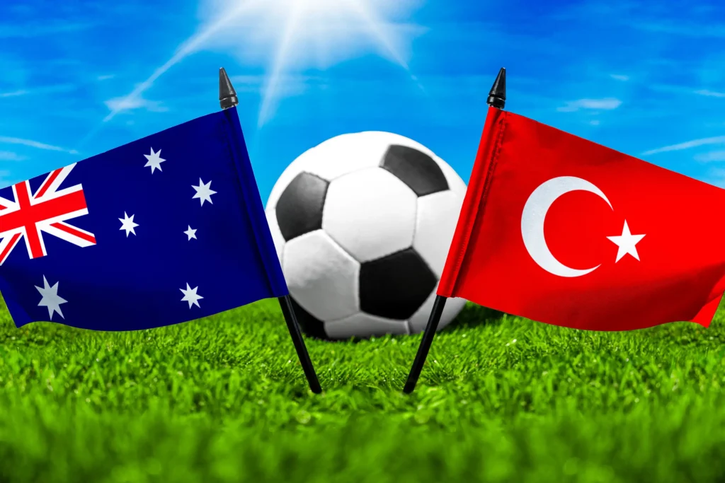 Australische und türkische Nationalflagge vor einem Fußball auf grünem Rasen unter blauem Himmel.