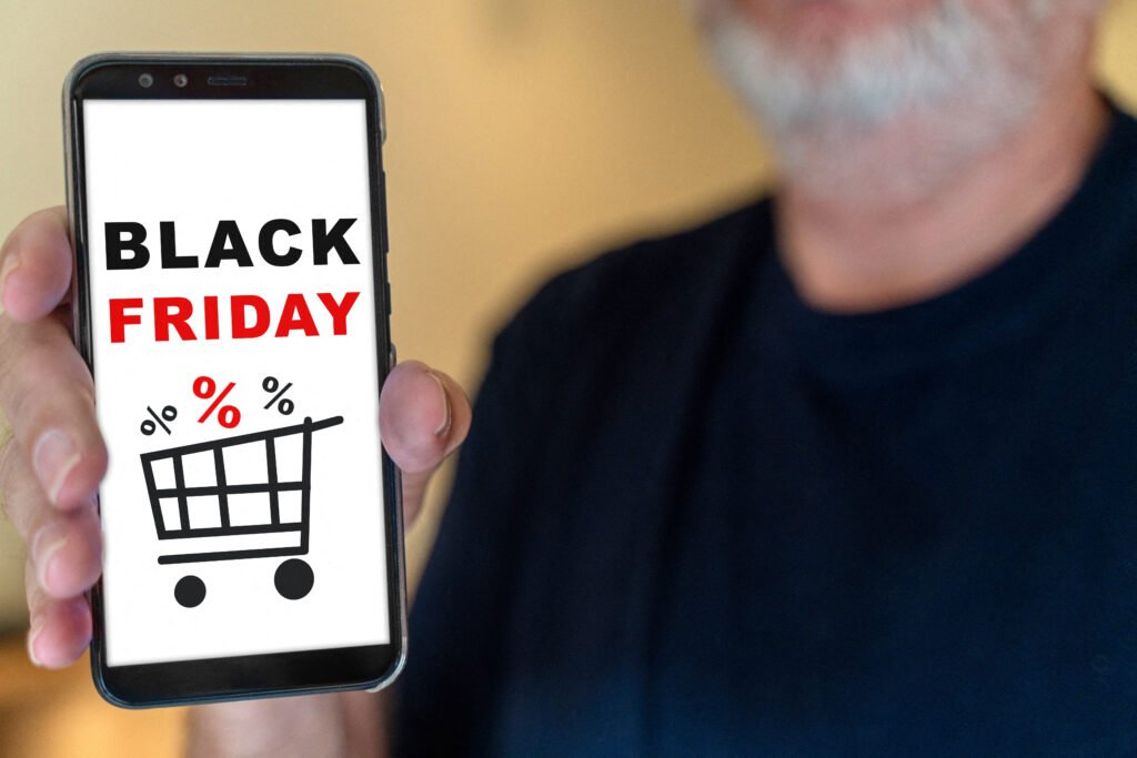 Black Friday Smartphone – Hand hält Smartphone mit Schriftzug BLACK FRIDAY und Einkaufswagensymbol