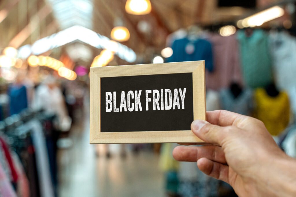 Black Friday Schild im Einkaufszentrum – Hand hält Schild mit Schriftzug BLACK FRIDAY vor Einkaufsmeile