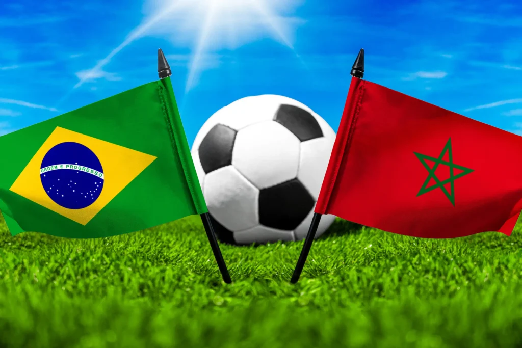 Nationalflaggen von Brasilien und Marokko vor einem Fußball auf grünem Rasen unter blauem Himmel.