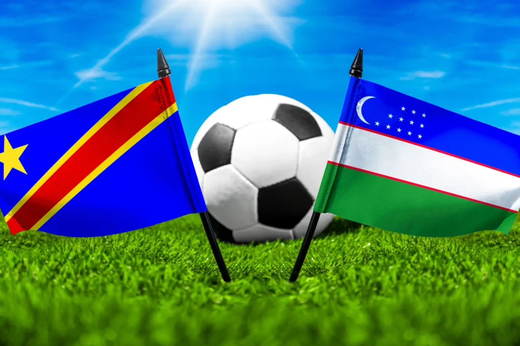 Flaggen der Demokratischen Republik Kongo und Usbekistans mit Fußball auf grünem Rasen unter blauem Himmel.