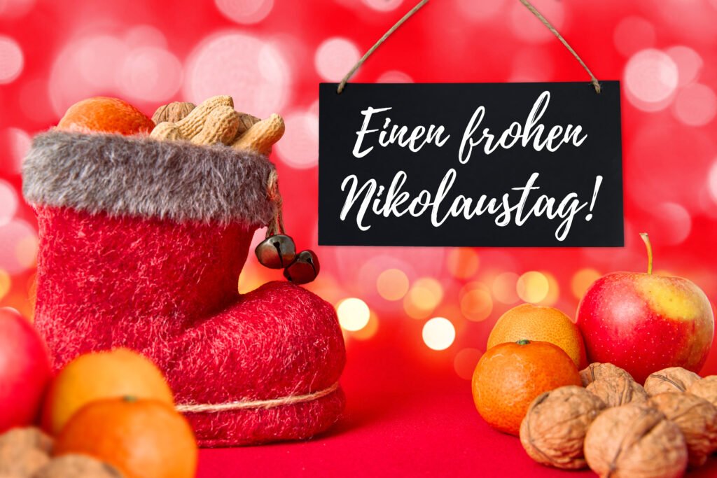 Einen frohen Nikolaustag als liebevoller Wunsch mit festlichem Nikolausstiefel, Obst und Nüssen vor rotem Hintergrund