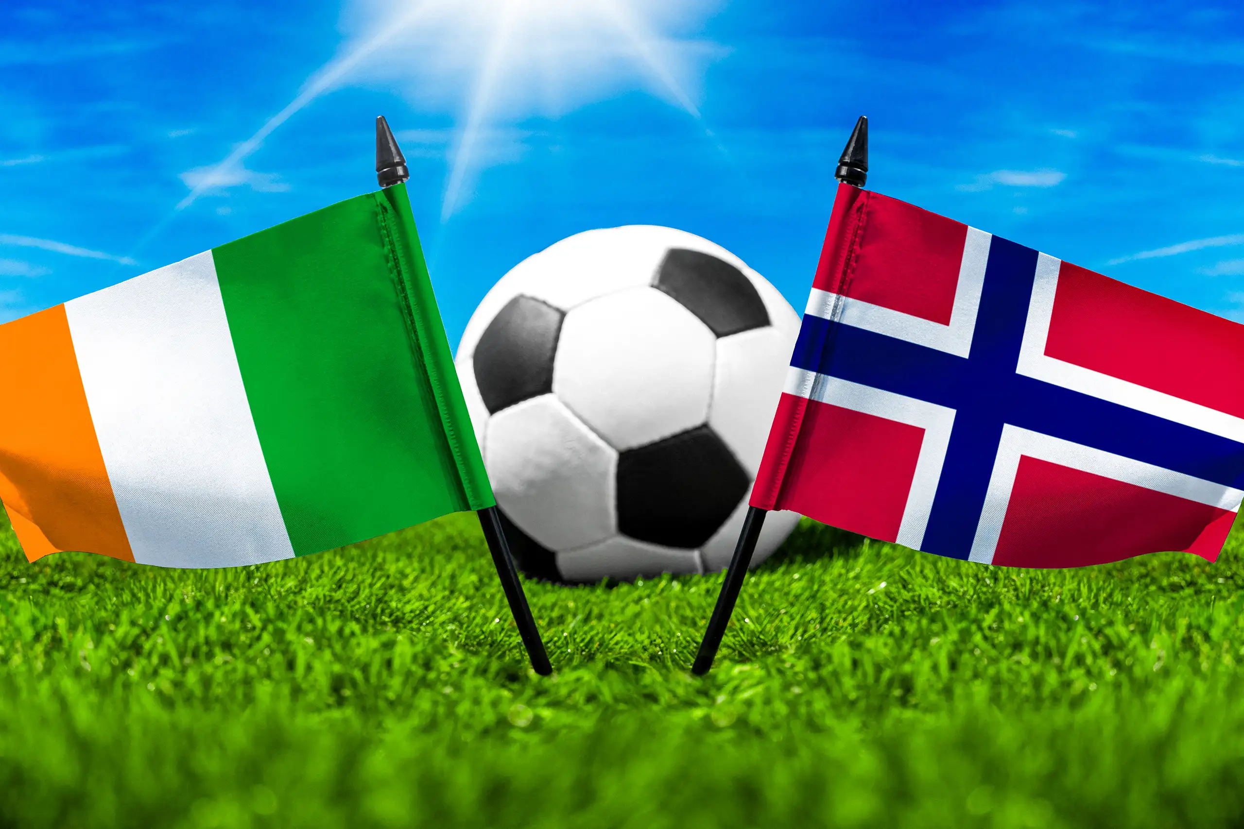 elfenbeinküste gegen norwegen mit nationalflaggen und fußball auf grünem rasen bei einer internationalen fußballbegegnung.