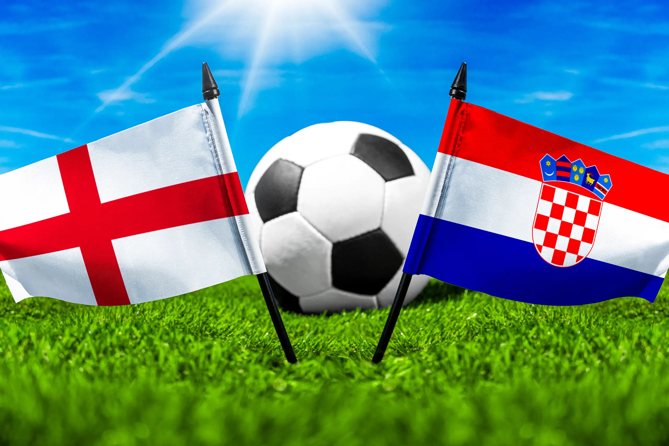 flaggen von england und kroatien mit fußball auf grünem rasen unter blauem himmel.