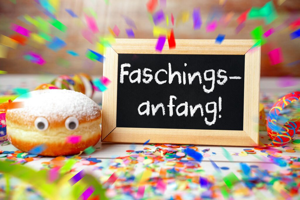 Faschingsanfang – Kreidetafel mit Schriftzug „Faschingsanfang!“ und Berliner mit Konfetti, Luftschlangen und Partydekoration.