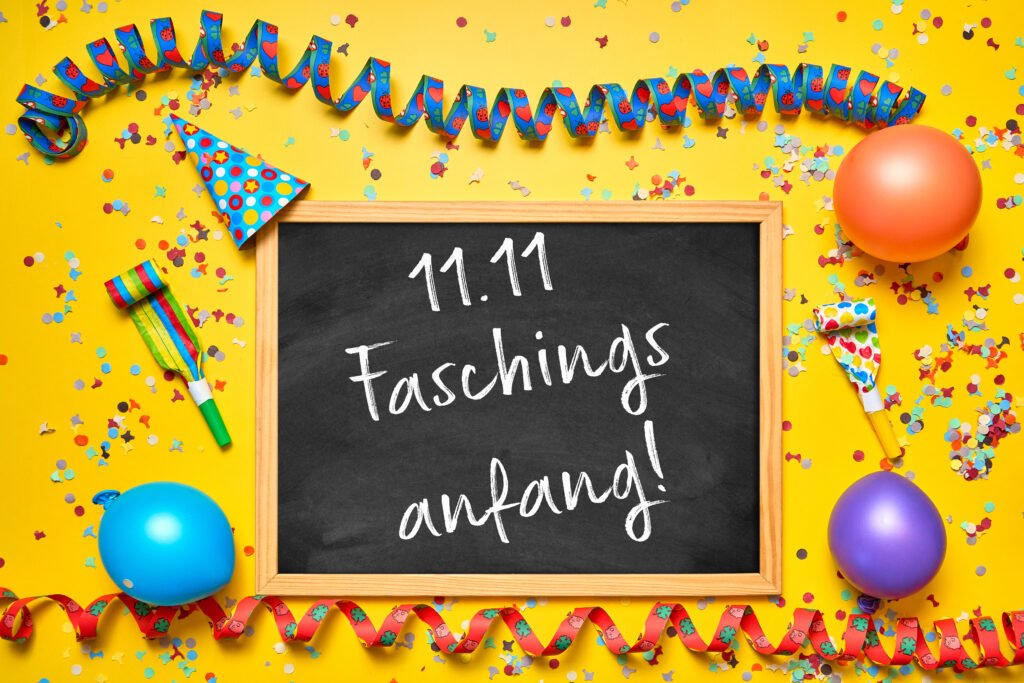 Faschingsanfang 11.11 – Tafel mit Schriftzug „11.11 Faschingsanfang!“ umgeben von buntem Konfetti und Partydeko