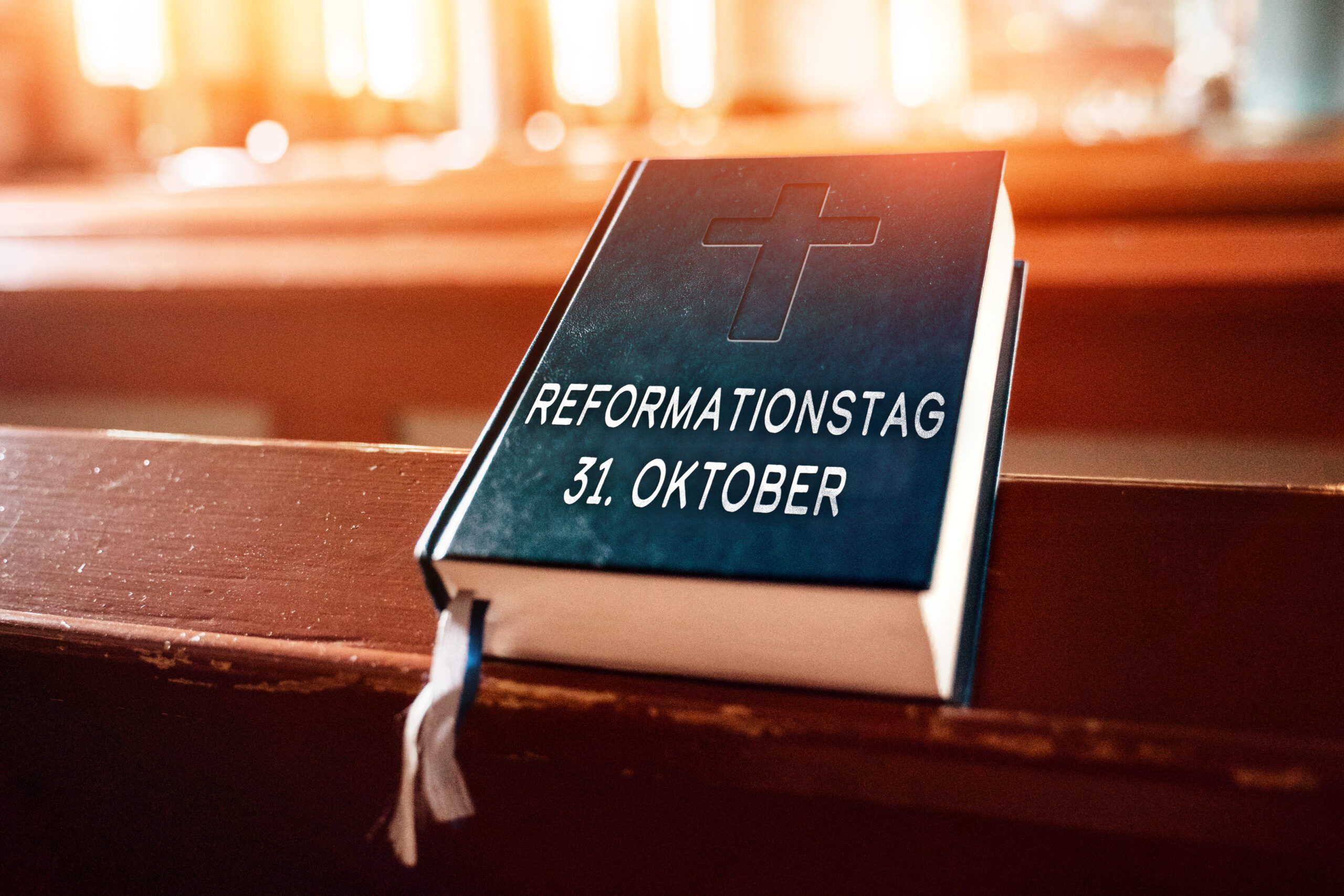 bibel mit kreuzprägung und aufschrift reformationstag 31. oktober liegt auf einer hölzernen kirchenbank im warmen sonnenlicht.