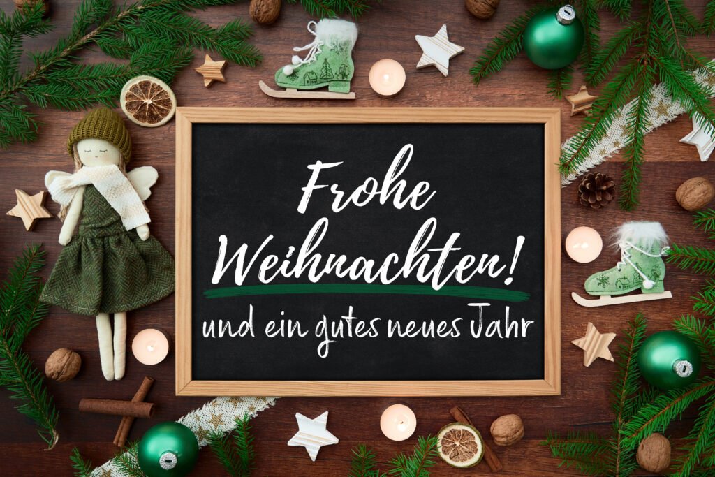 Grüße zu Weihnachten – festliche Weihnachtsdeko mit Engel, grüner Kugel, Kerzen und Tannenzweigen
