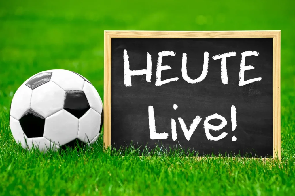 Tafel mit der Aufschrift Heute Live neben Fußball auf grünem Rasen.