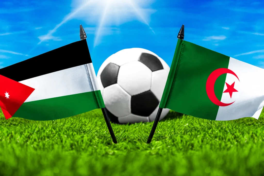 Jordanien gegen Algerien mit Fußball auf Rasen und den Nationalflaggen beider Länder unter blauem Himmel.