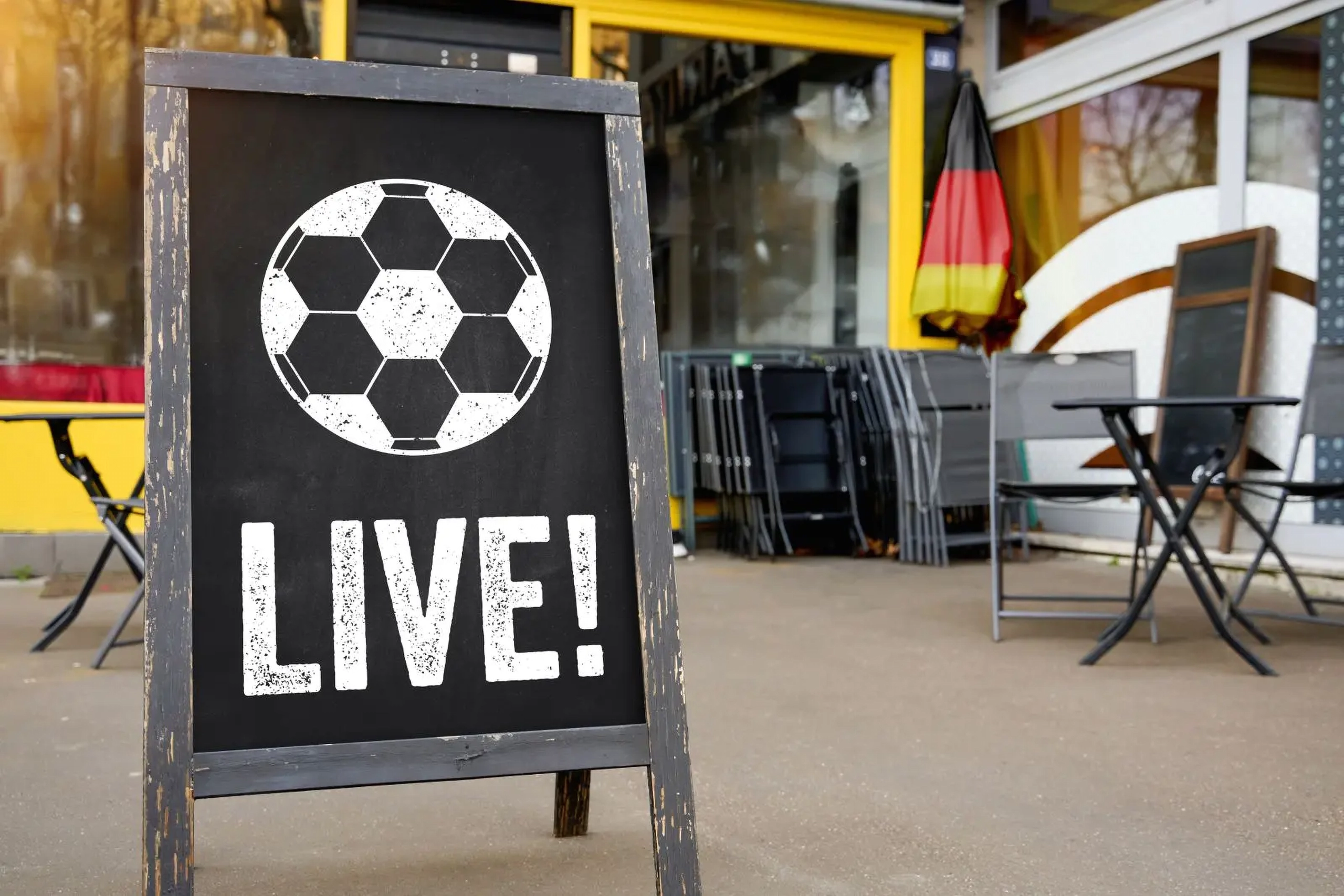 fußball live schild vor einem restaurant mit deutschland fahne für live-übertragung und public viewing.