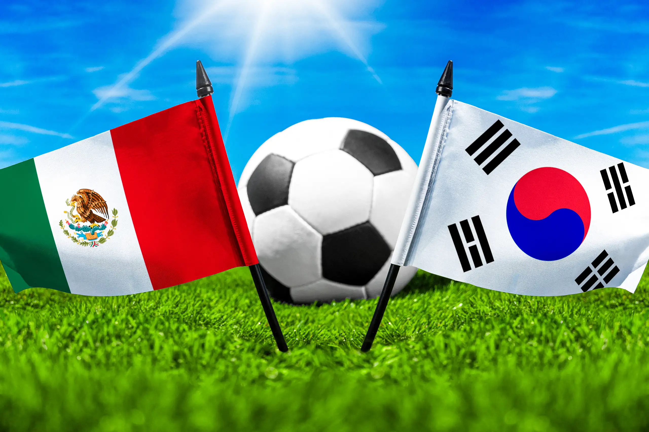 flaggen von mexiko und südkorea mit fußball auf grünem rasen unter blauem himmel.