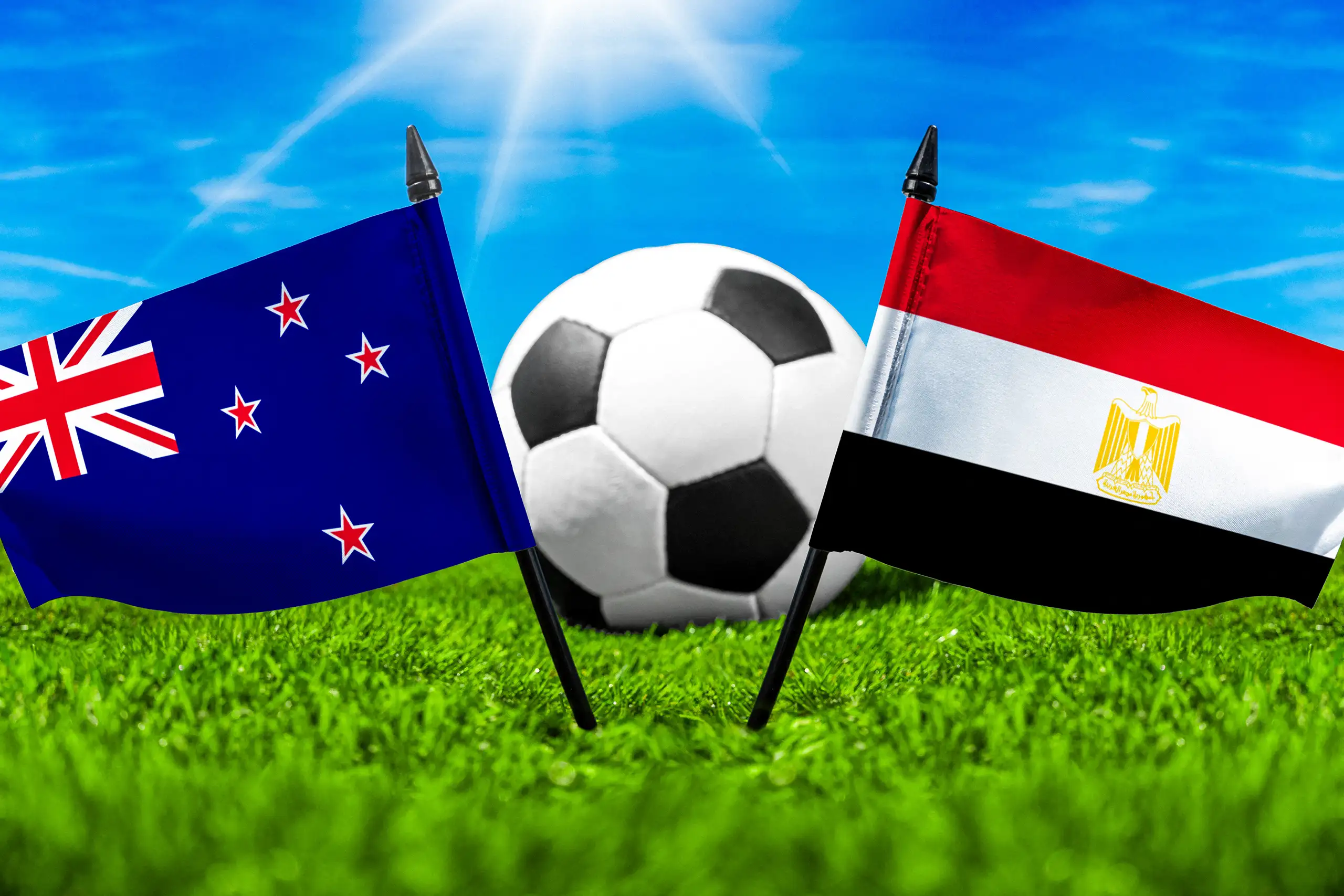 flaggen von neuseeland und ägypten mit fußball auf grünem rasen unter blauem himmel.