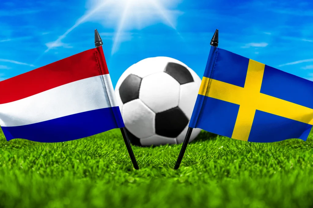 Flaggen der Niederlande und Schwedens mit Fußball auf grünem Rasen unter blauem Himmel.