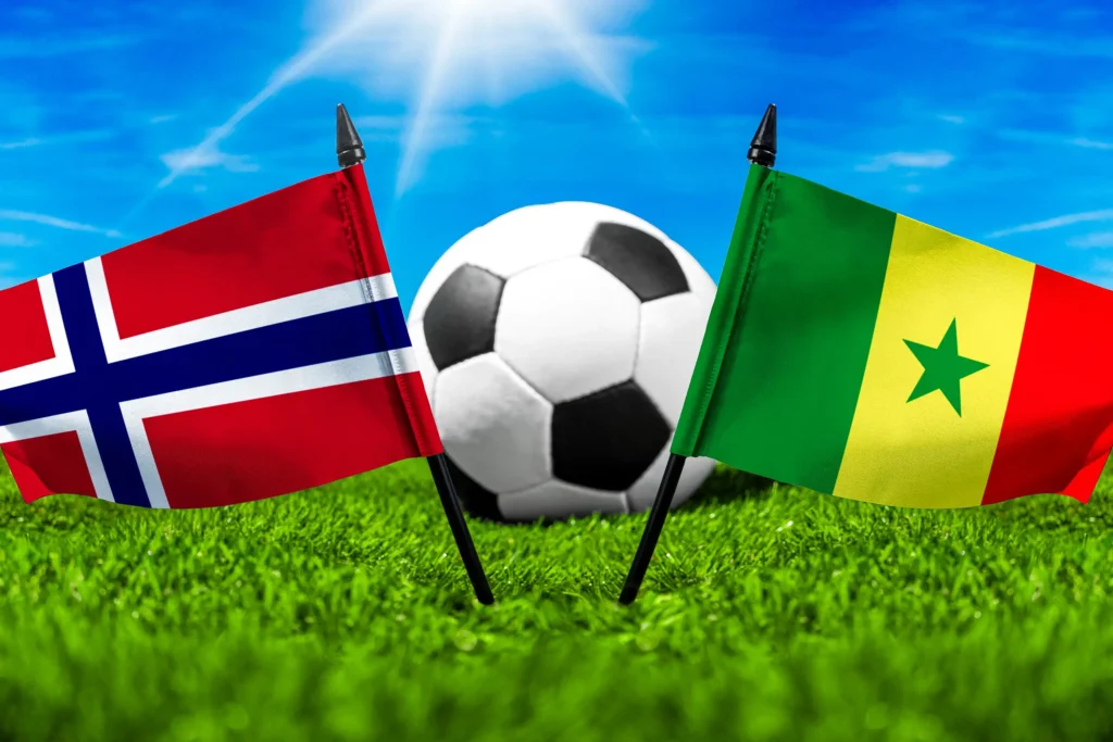 Norwegen Senegal Fußballspiel mit Fußball zwischen norwegischer und senegalesischer Nationalflagge auf grünem Spielfeldrasen.