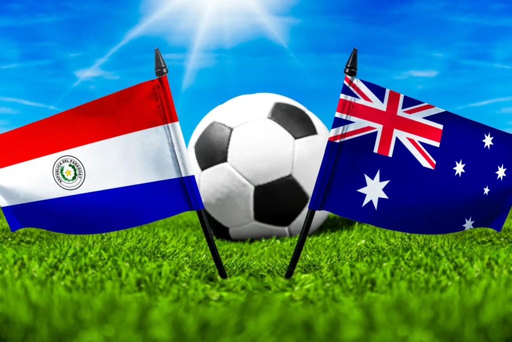 Paraguayische und australische Flagge vor einem Fußball auf grünem Rasen unter blauem Himmel.