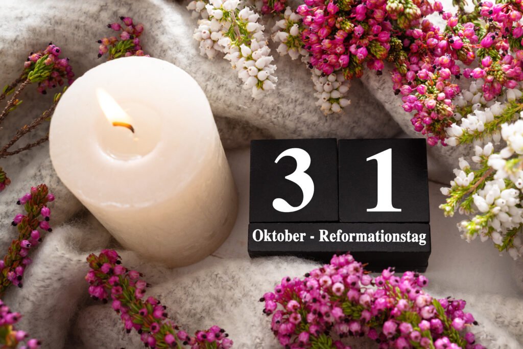 Reformationstag Grußbild mit brennender Kerze, violetten Heideblüten und Kalenderblock mit Datum 31. Oktober – Reformationstag.