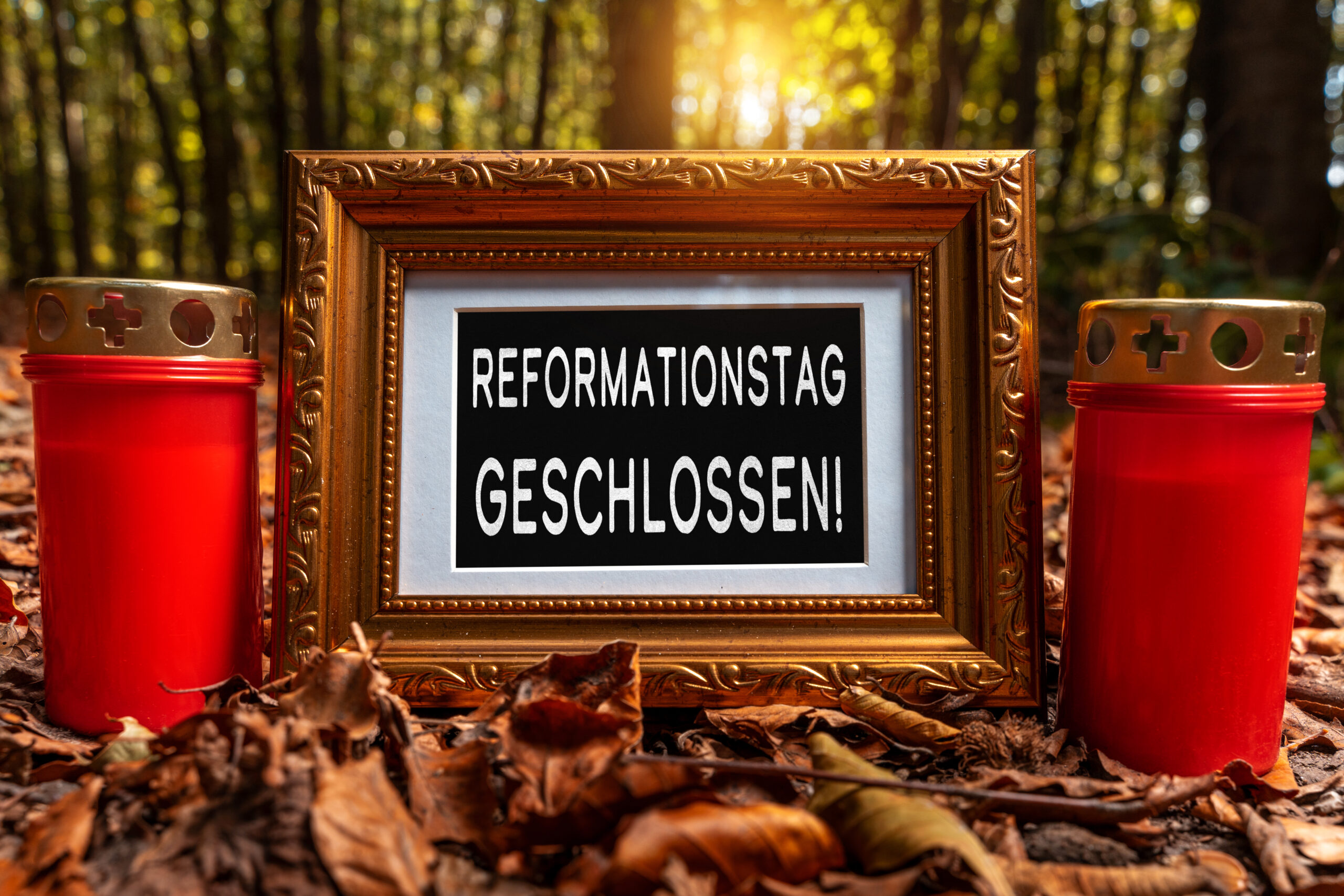 reformationstag geschlossen schild im goldenen rahmen zwischen zwei roten grablichtern im herbstlichen wald mit sonnenlicht und laub.