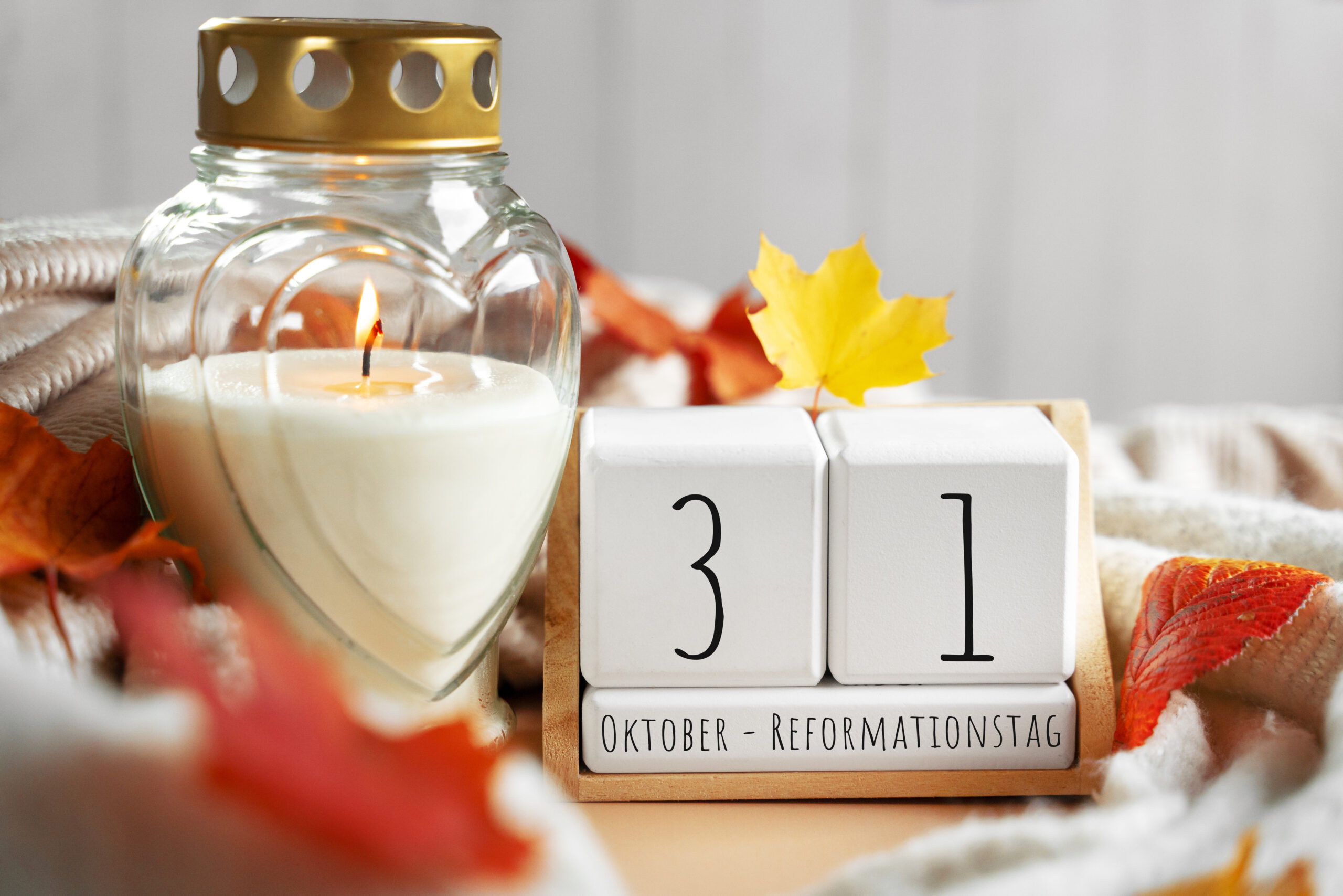 reformationstag bild mit brennender kerze, herbstblättern und kalenderblock mit datum 31. oktober