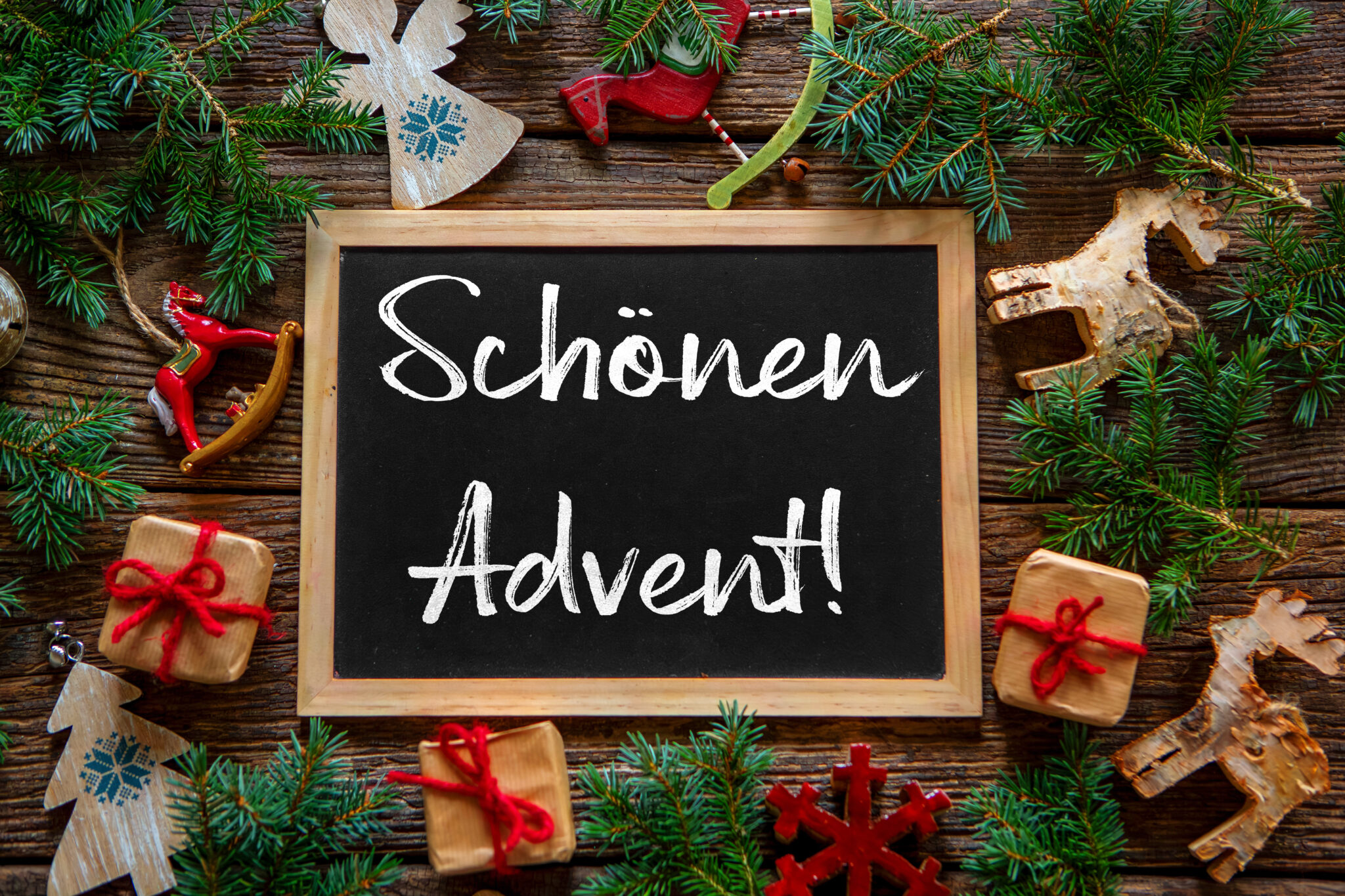 schönen advent auf tafel mit tannenzweigen, holzfiguren und weihnachtlicher deko