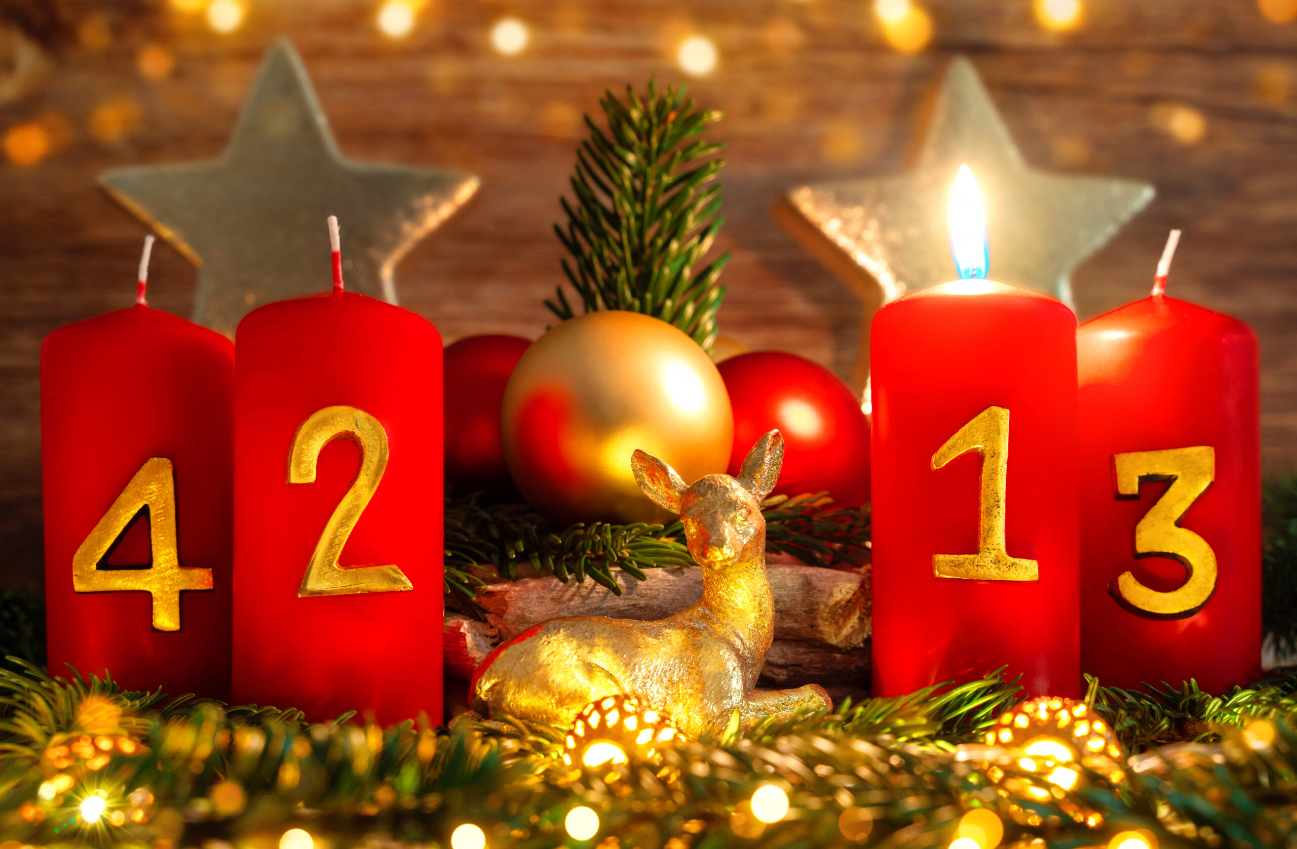 rote adventskerzen mit goldenen zahlen zum ersten 1. advent, umgeben von tannenzweigen und weihnachtskugeln