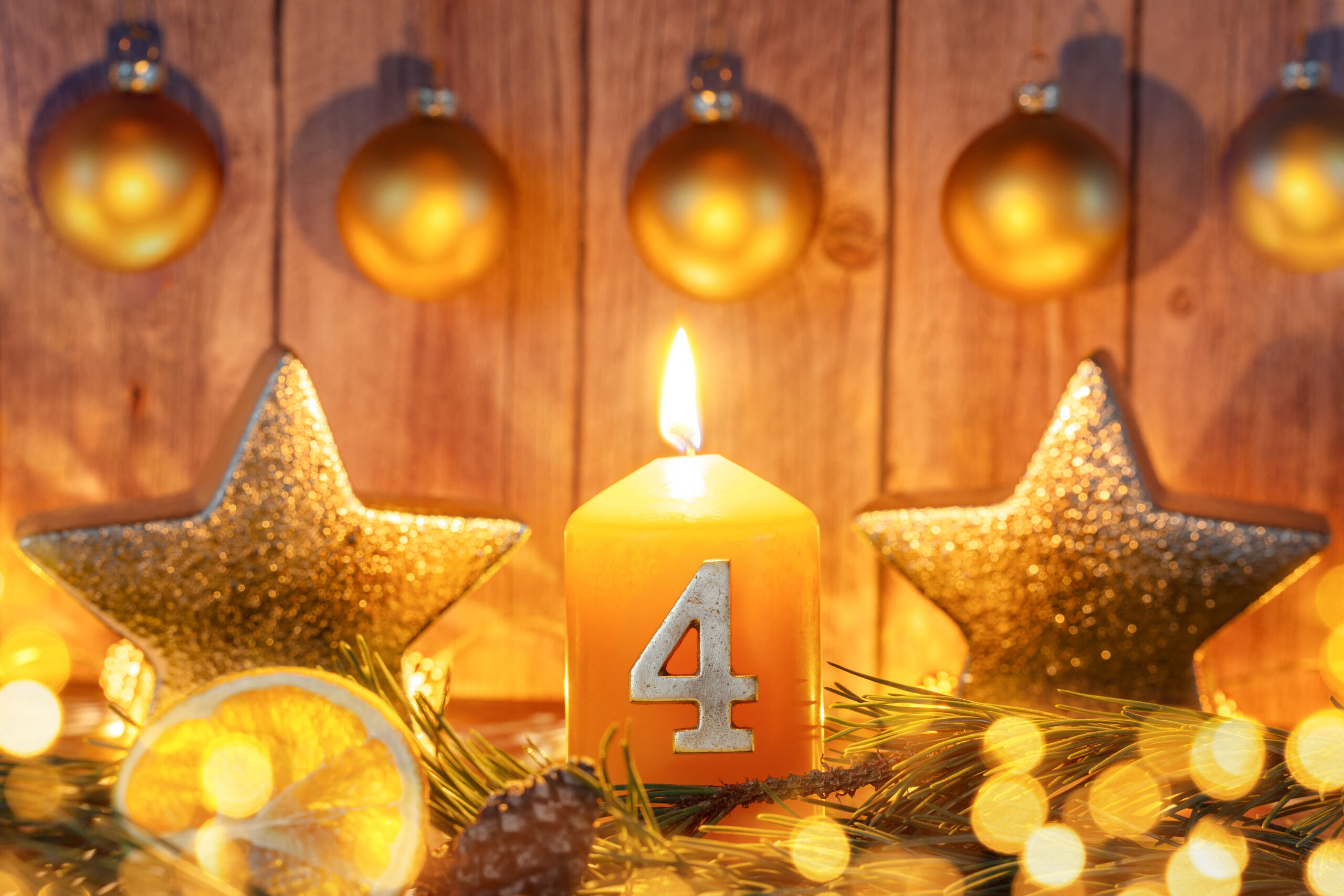 4 advent kerze mit goldener dekoration und leuchtender vierter adventskerze