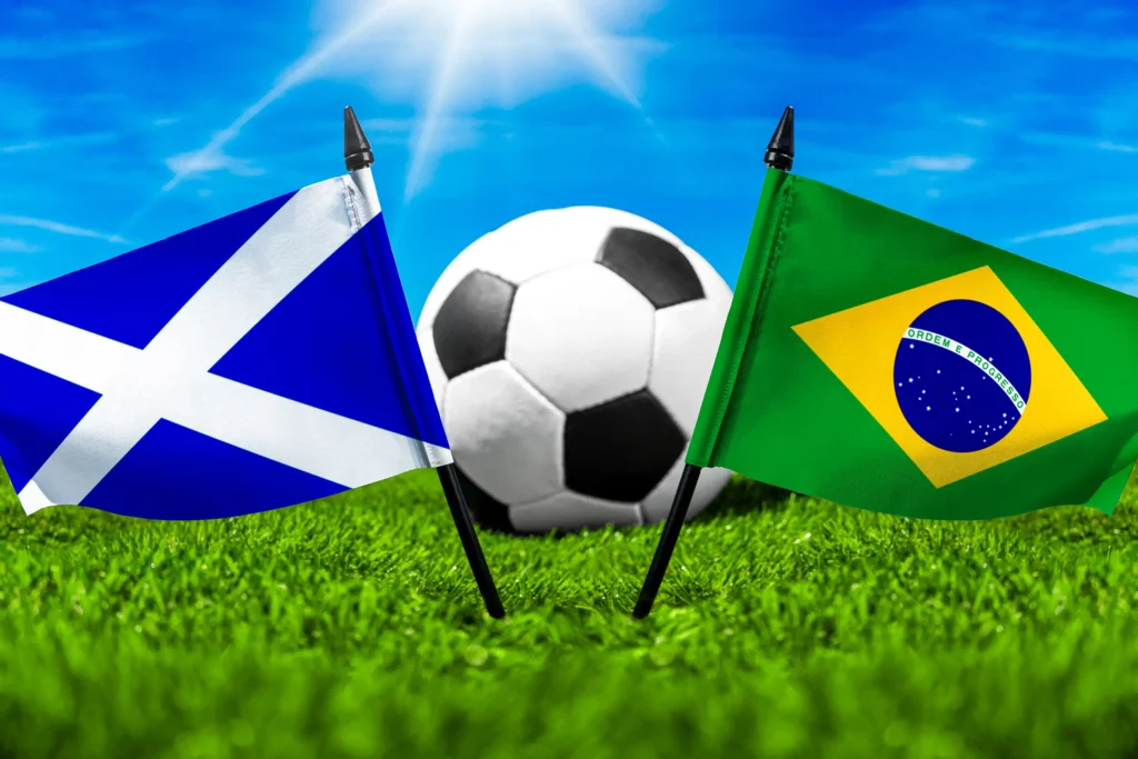 Schottland Brasilien Fußballspiel mit Fußball zwischen schottischer und brasilianischer Nationalflagge auf grünem Spielfeldrasen.