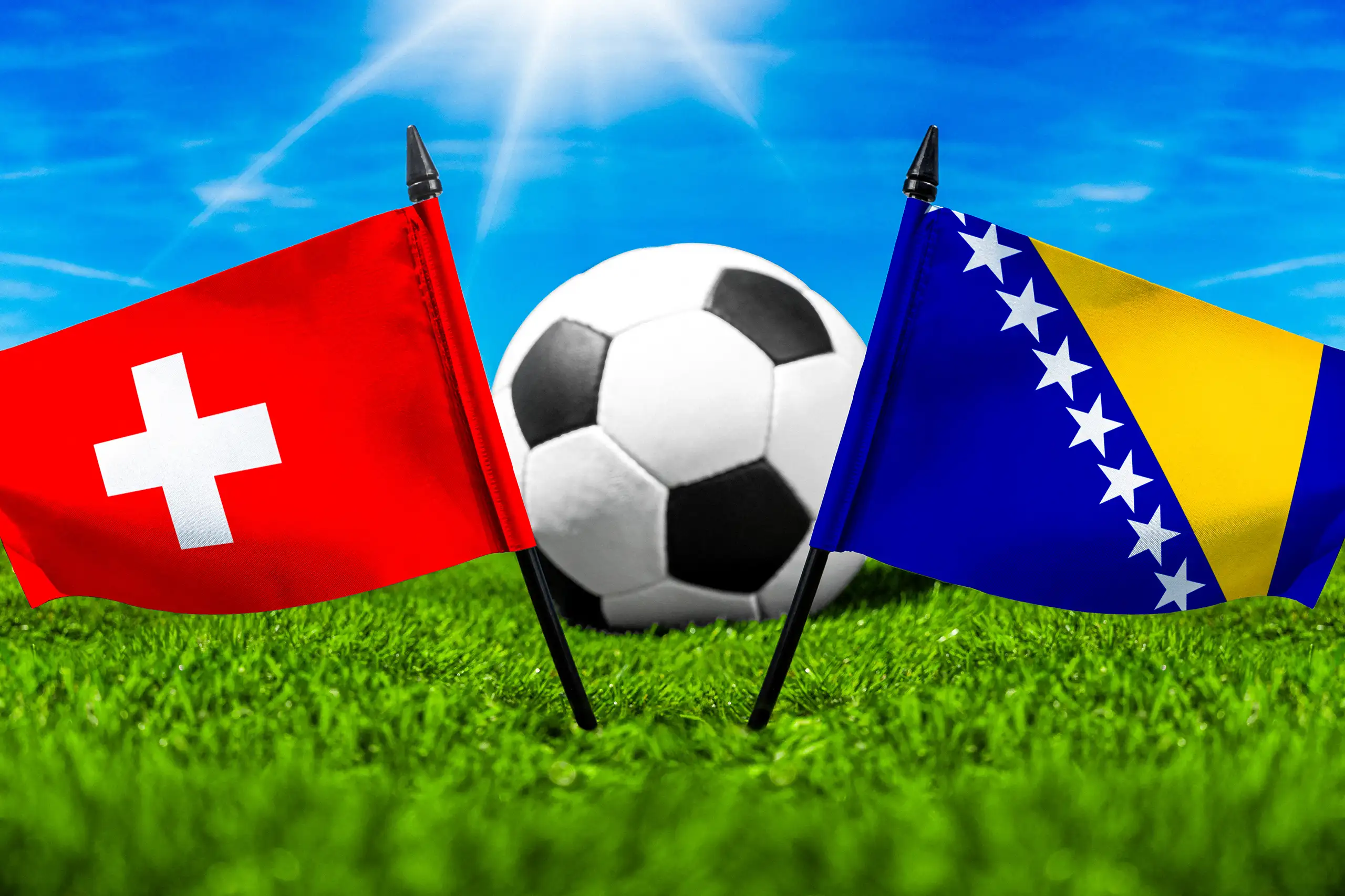 schweiz bosnien fußballspiel mit fußball zwischen den nationalflaggen der schweiz und bosnien-herzegowina auf grünem spielfeldrasen.