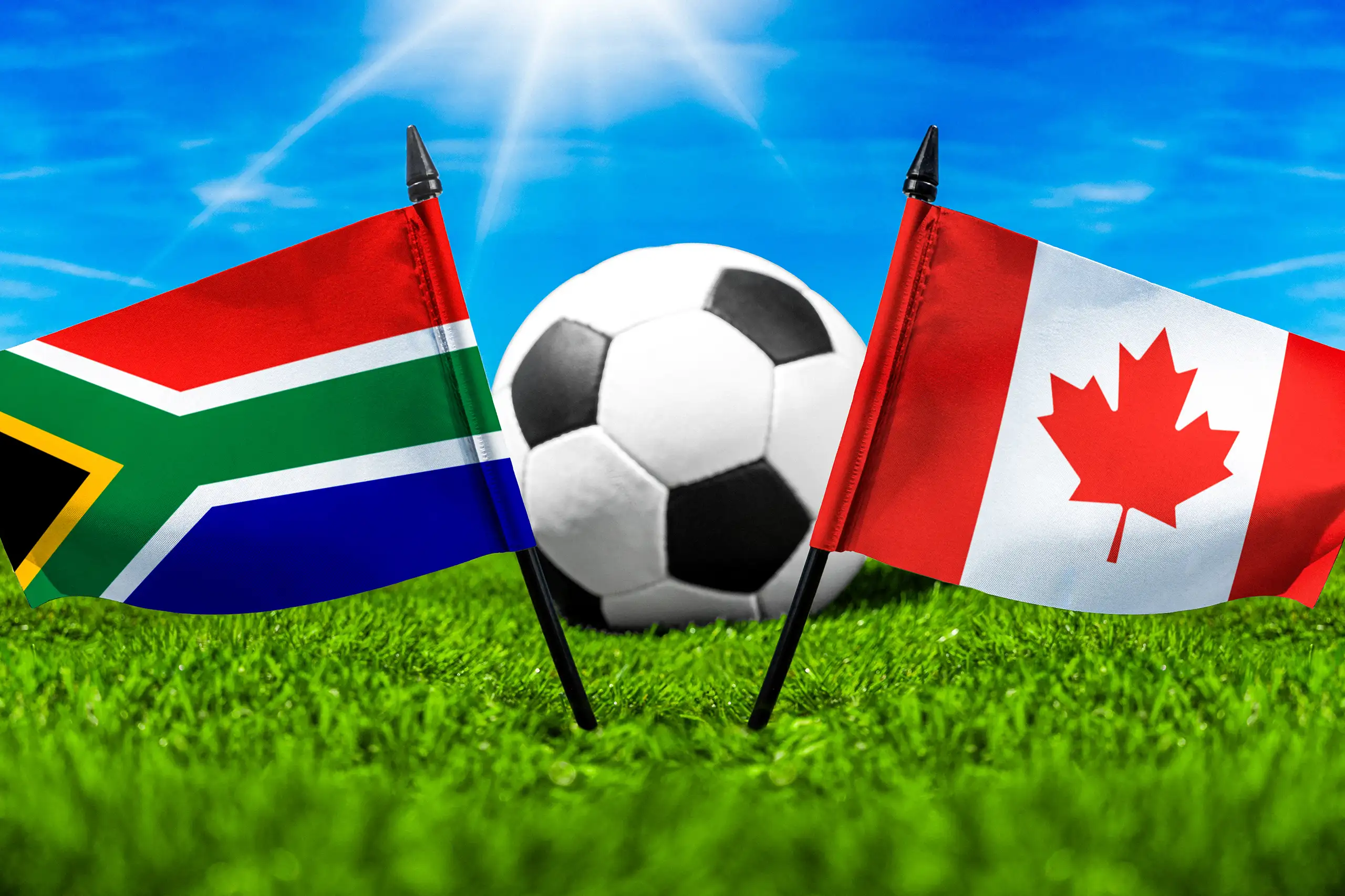 südafrika gegen kanada mit nationalflaggen und fußball auf grünem rasen bei einem internationalen fußball-länderspiel.