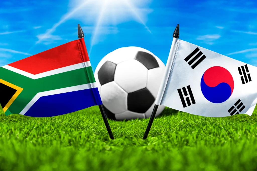 Südafrikanische und südkoreanische Flagge mit Fußball auf einem Spielfeld im Freien.