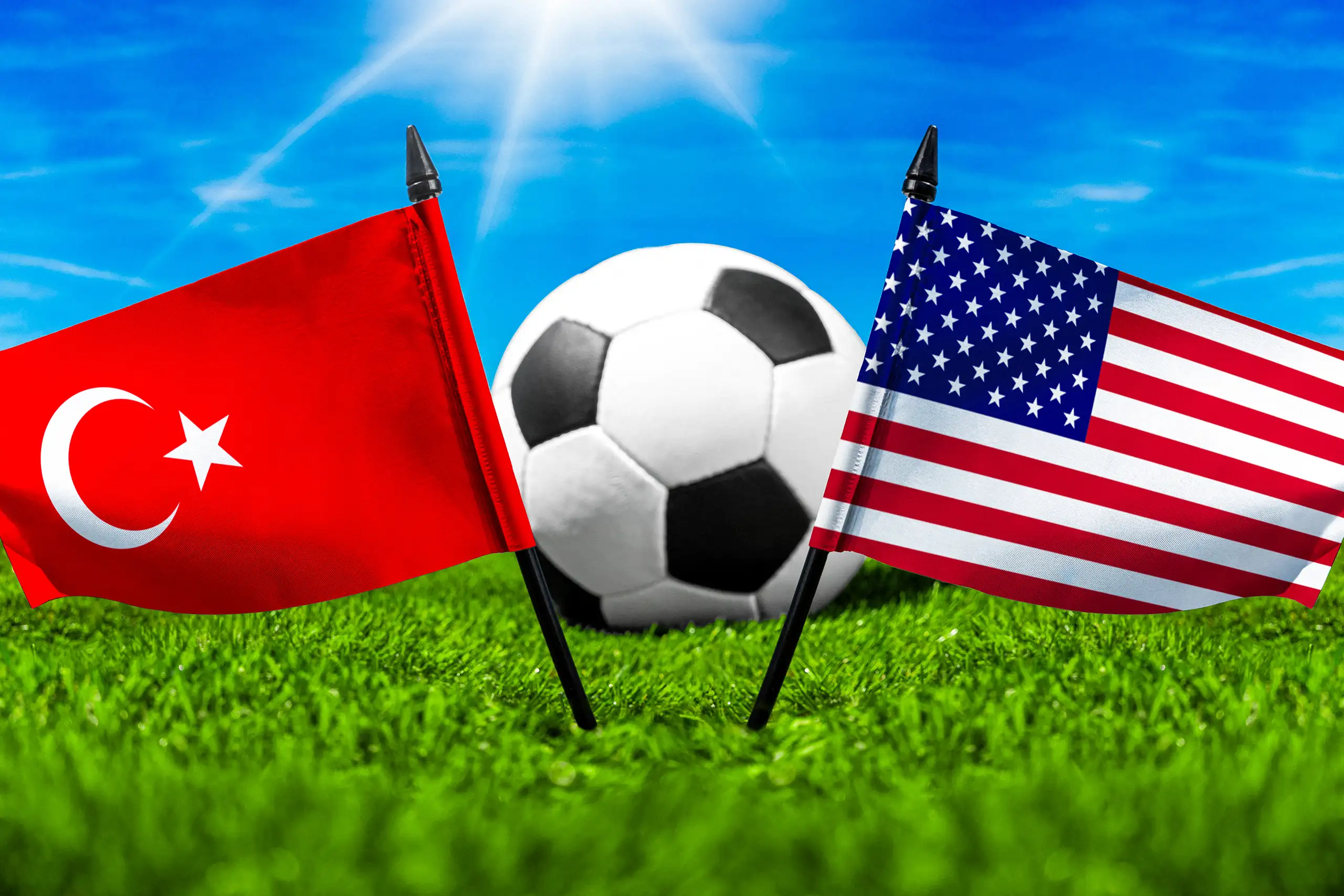 türkische und us-amerikanische nationalflagge neben einem fußball auf einem spielfeld mit grünem rasen.