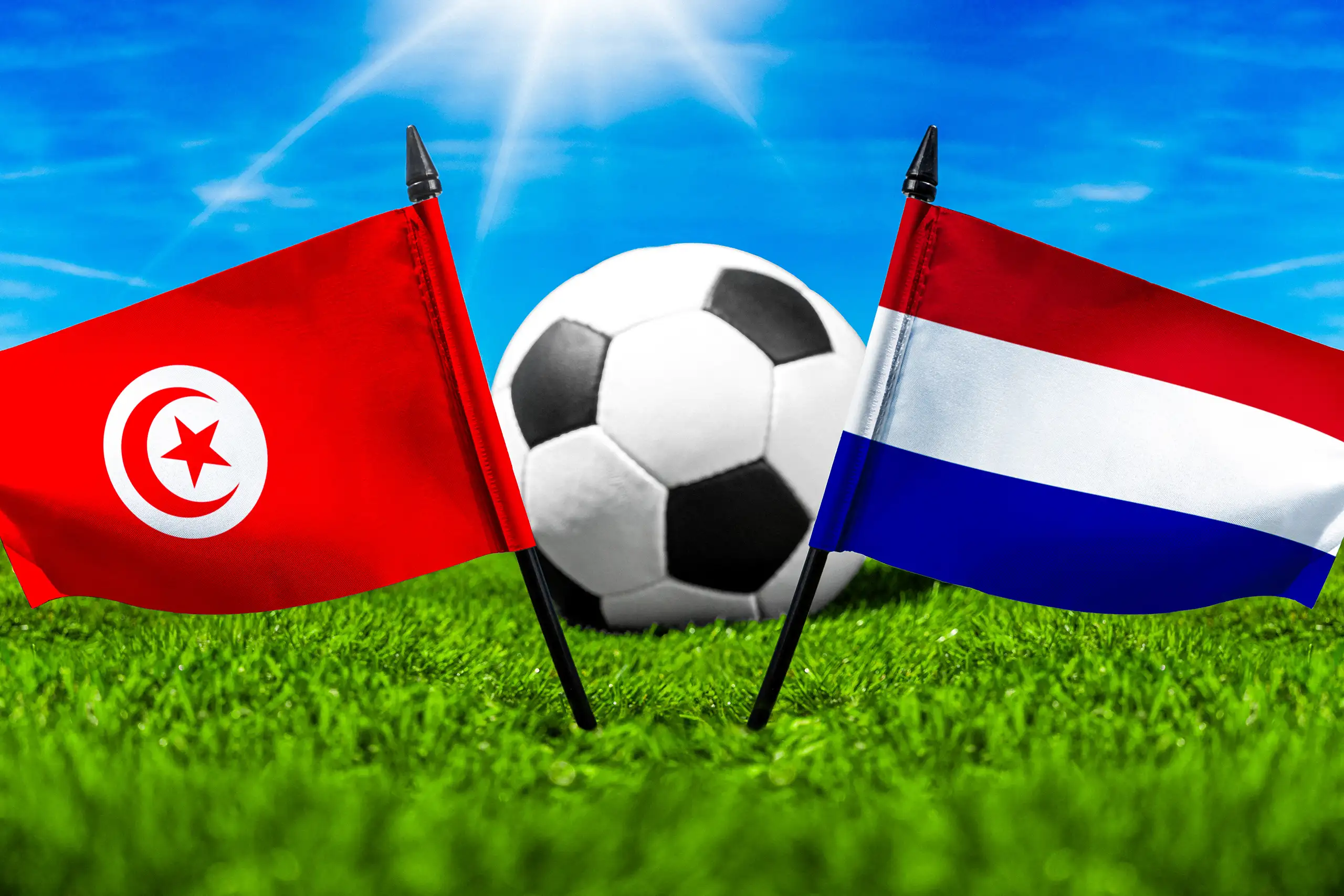 tunesien niederlande fußballspiel mit fußball zwischen den nationalflaggen von tunesien und den niederlanden auf grünem rasen.