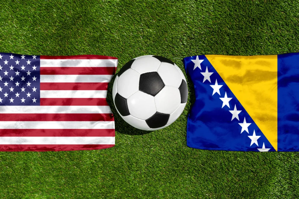 USA gegen Bosnien und Herzegowina mit Nationalflaggen und Fußball auf grünem Rasen als Motiv für ein internationales Fußball-Länderspiel.