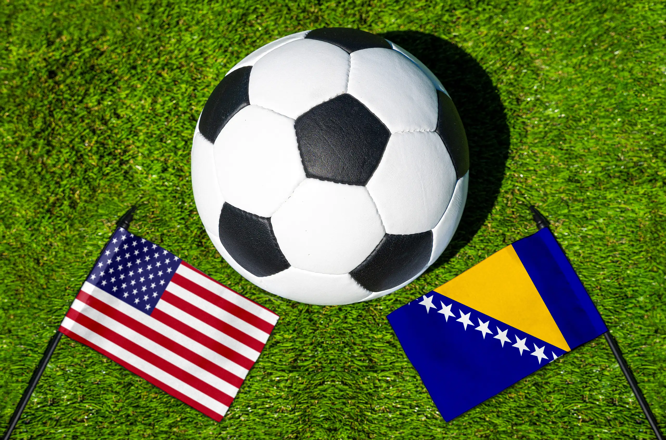 usa gegen bosnien und herzegowina mit fußball und nationalflaggen auf grünem rasen als motiv für ein internationales fußball-länderspiel.