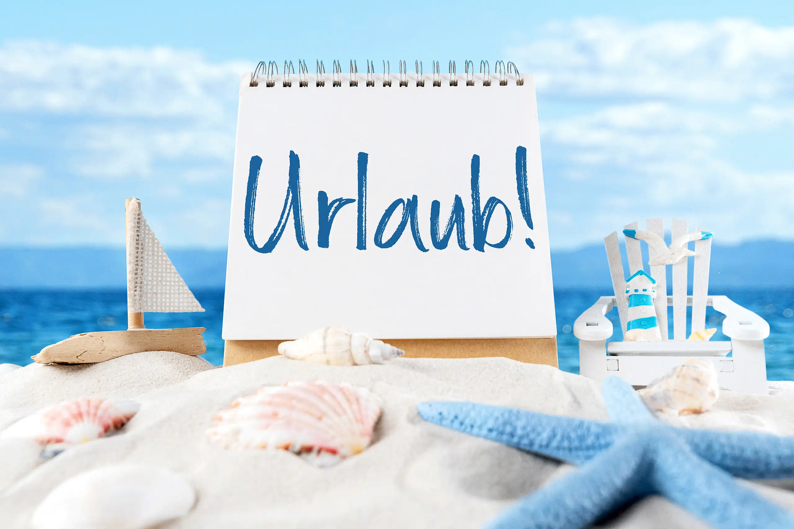 Urlaub Bild mit blauem Schriftzug auf weißem Notizblock, Muscheln, Seestern, Sand und Meer