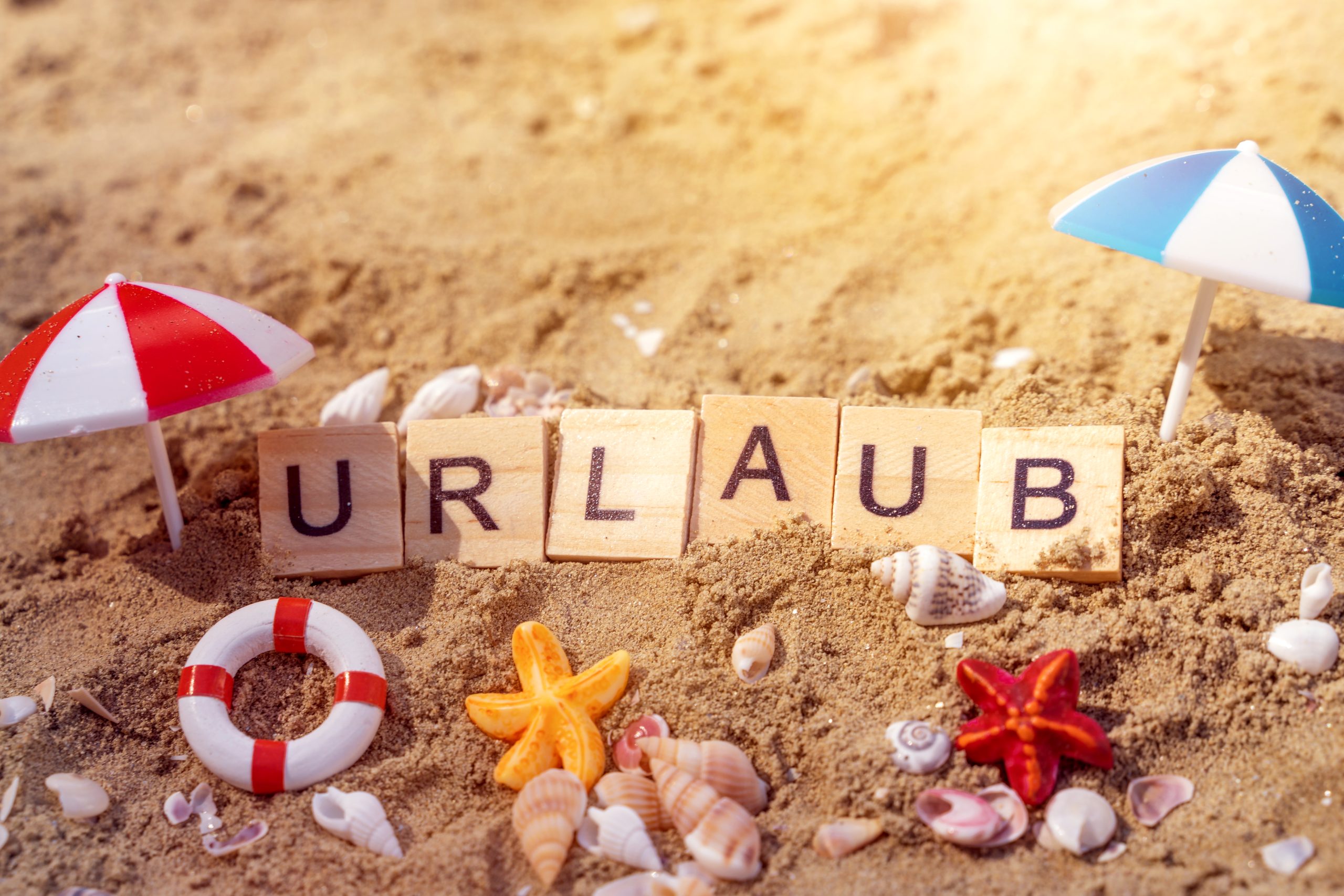 urlaub bilder: holzbuchstaben im sand mit dem wort urlaub