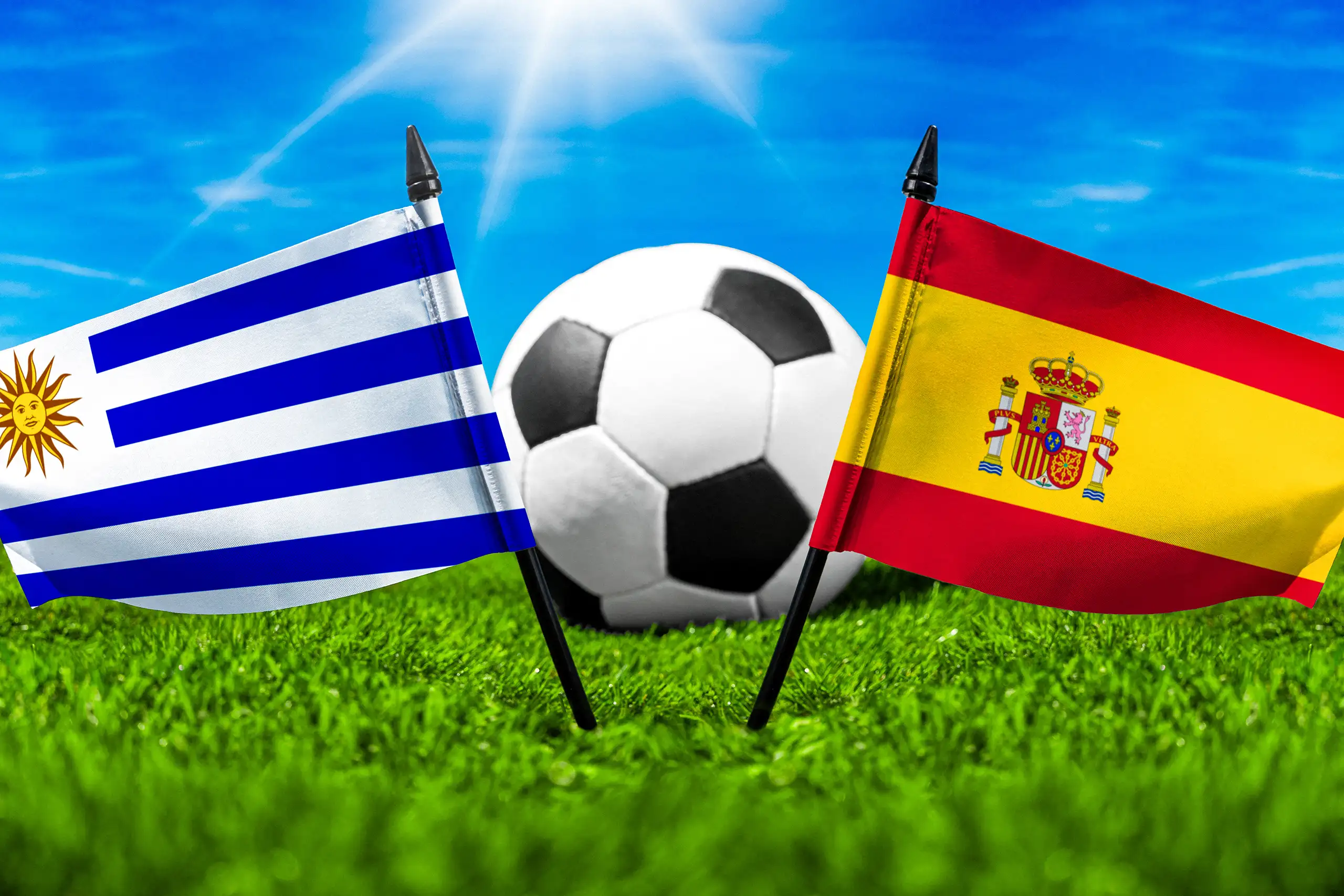 flaggen von uruguay und spanien neben einem fußball auf einem fußballfeld.