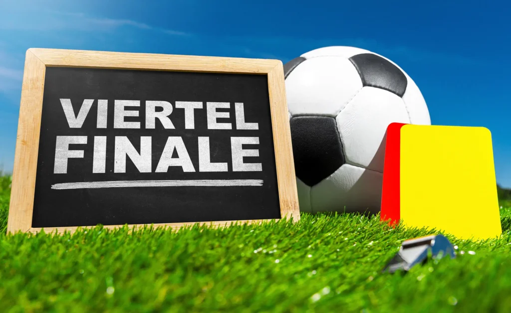 Tafel mit Viertelfinale neben Fußball, Schiedsrichterkarten und Pfeife auf Rasen.