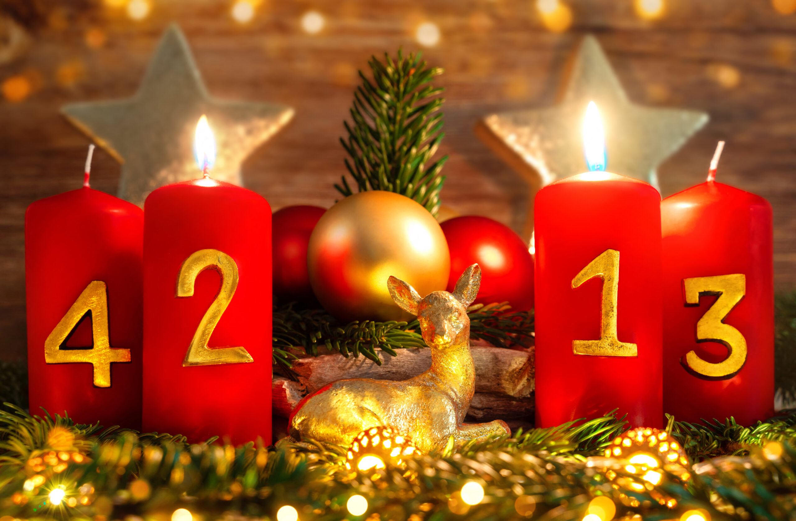 rote kerzen auf einem festlichen adventskranz zum 2. advent mit goldener deko und tannenzweigen.