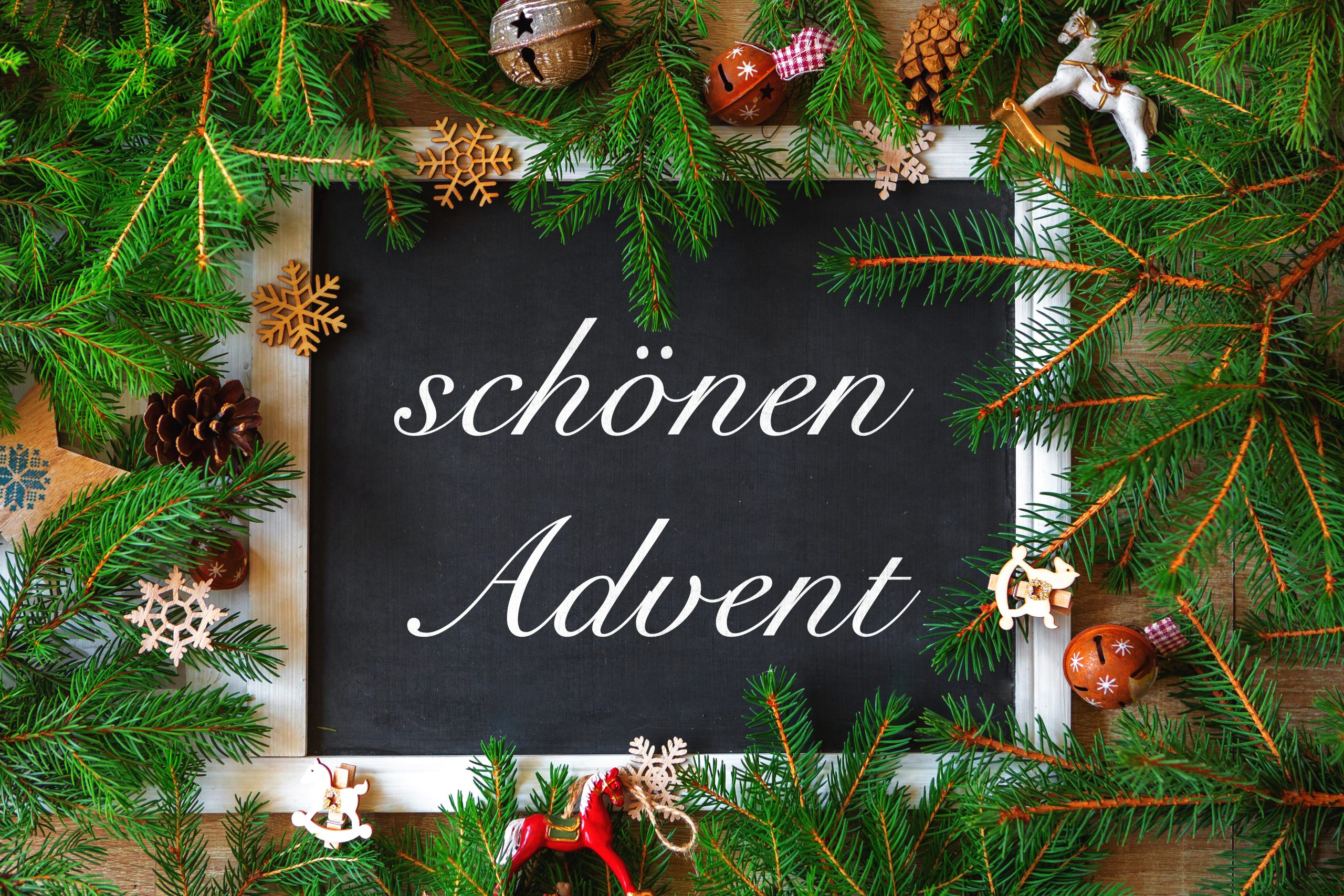 schönen advent schriftzug auf einer tafel umgeben von grünen tannenzweigen