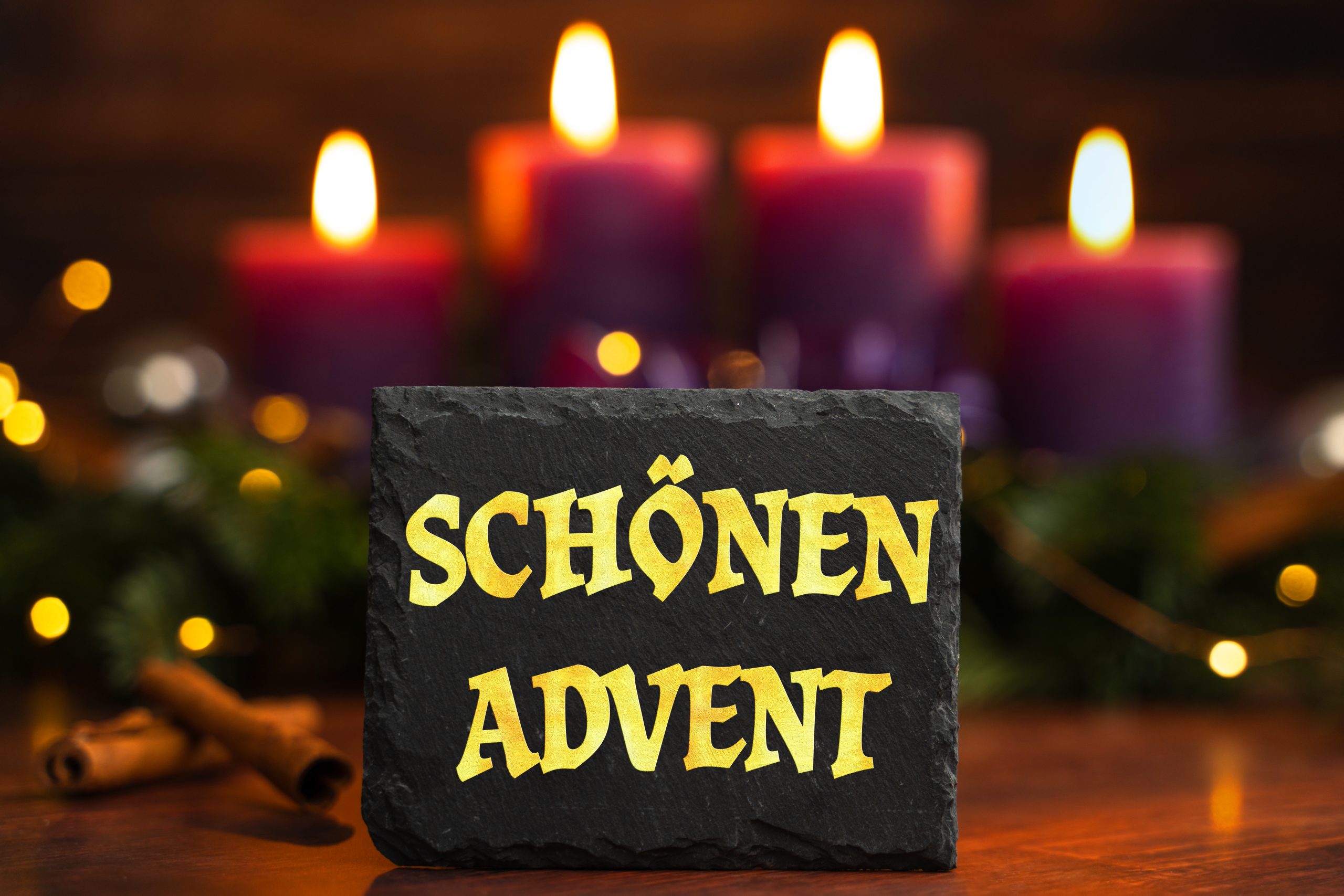 schönen advent gruß auf einer tafel vor adventskranz