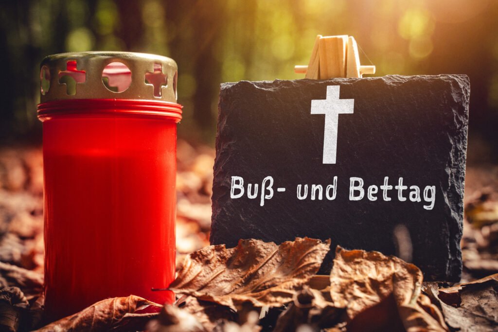 Buß- und Bettag – rotes Grablicht mit Kreuz im herbstlichen Wald