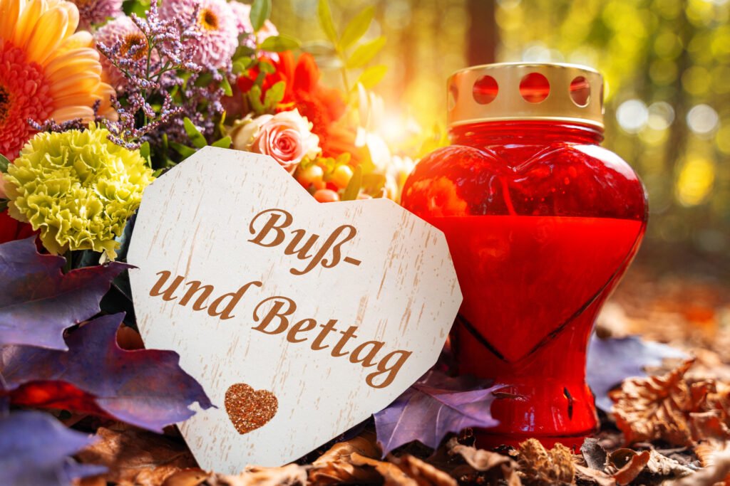 Buß- und Bettag Gruß mit Blumen, rotem Licht und Herzschild im Herbst