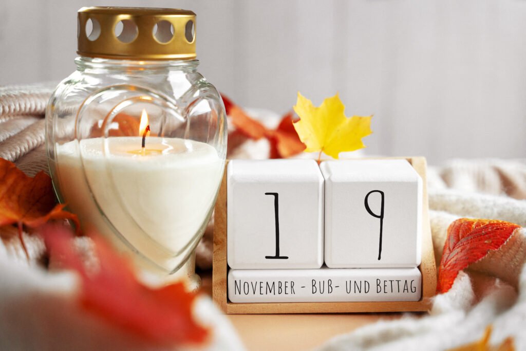 Weiße Kerze mit Herzglas und Herbstlaub zum Buß- und Bettag am 19. November