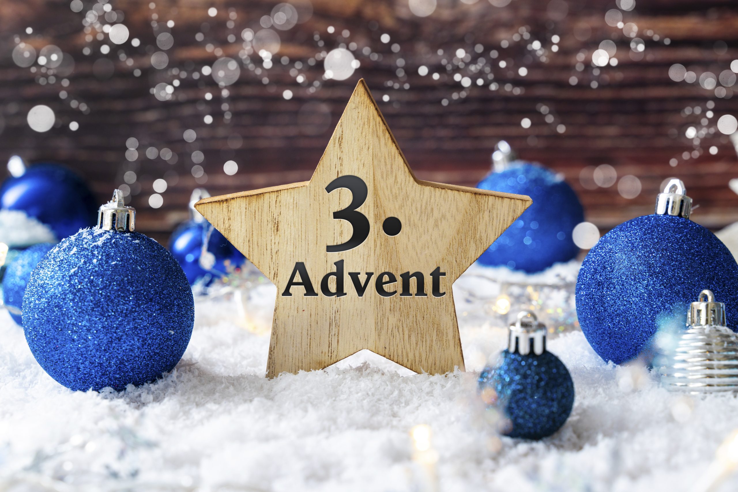 3. advent – holzstern mit schriftzug umgeben von blauer weihnachtsdekoration im schnee.