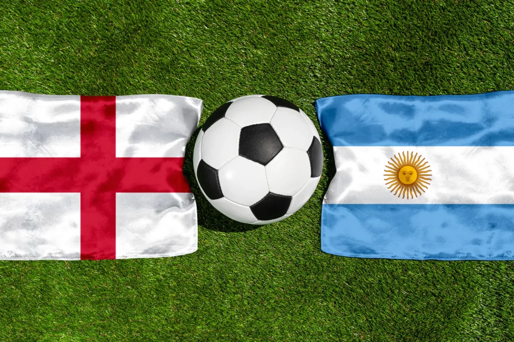 England - Argentinien mit Fußball zwischen den Nationalflaggen auf grünem Rasen in der Draufsicht.