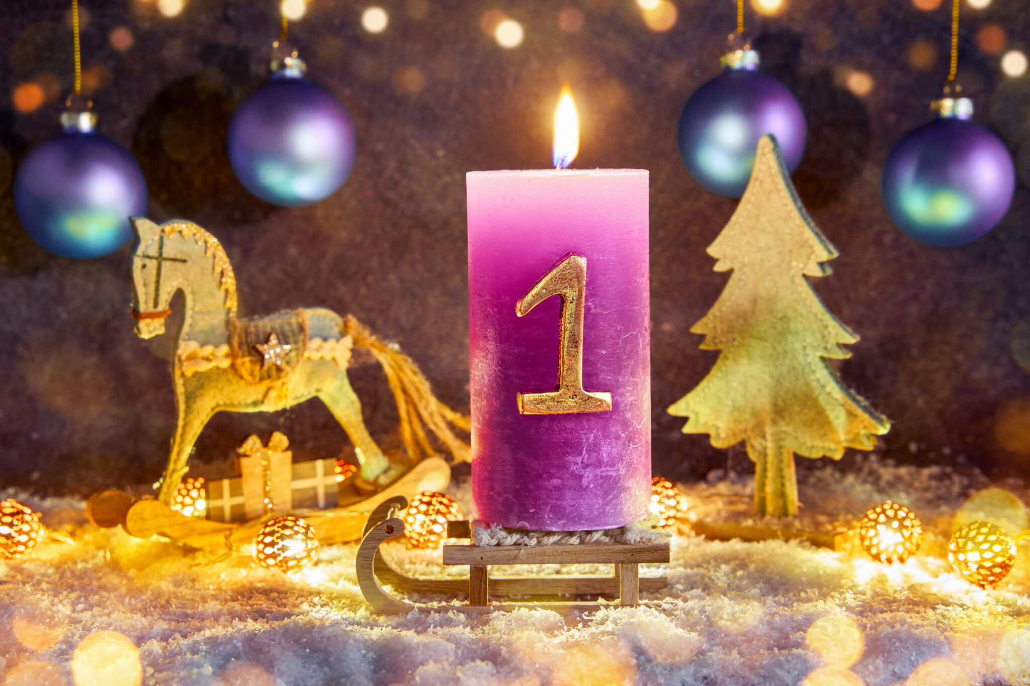 lila kerze zum 1. advent mit goldzahl und weihnachtlicher deko