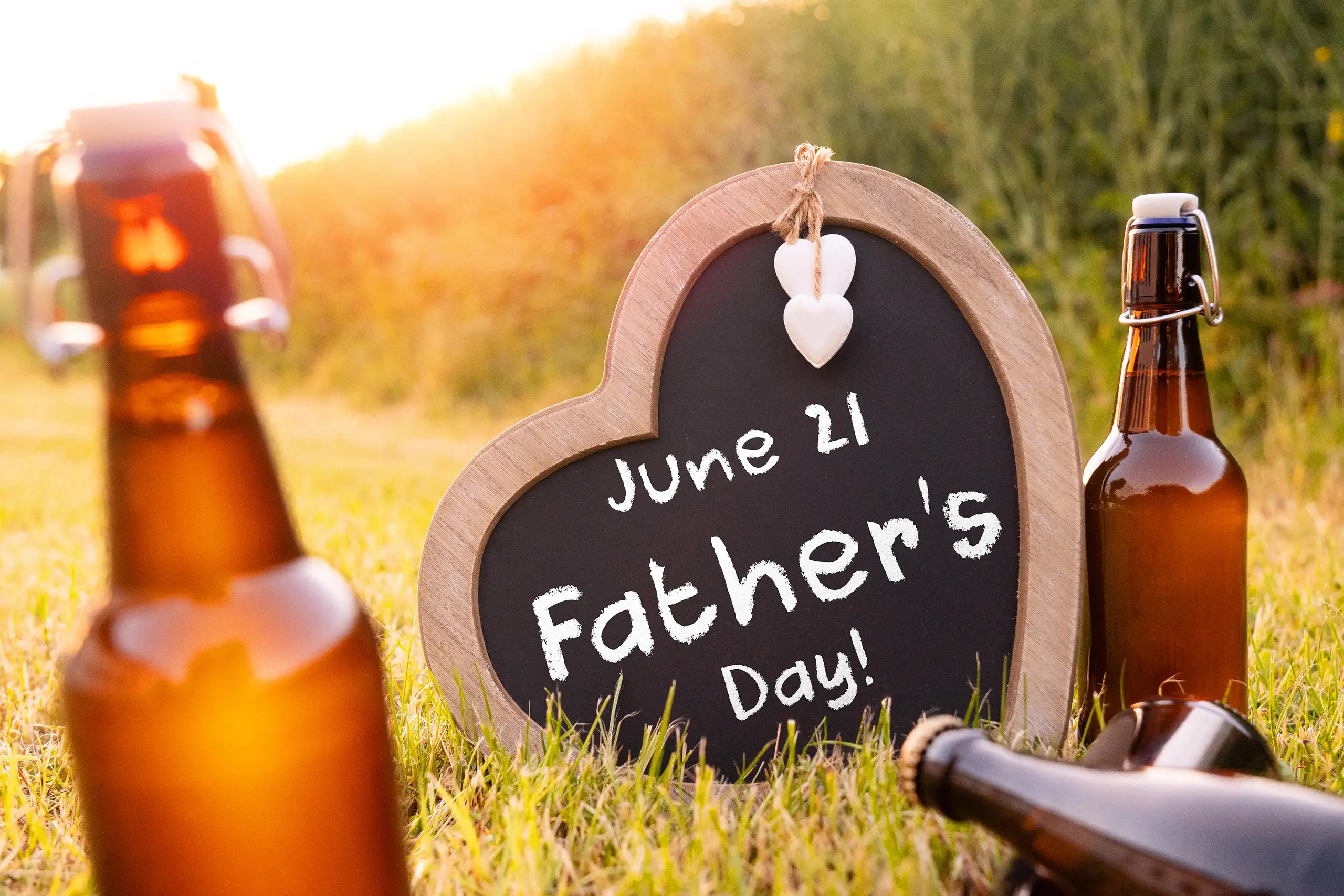 FATHERS DAY 2026 BILDER father's day 2026 sign in a heart-shaped chalkboard surrounded by beer bottles outdoors